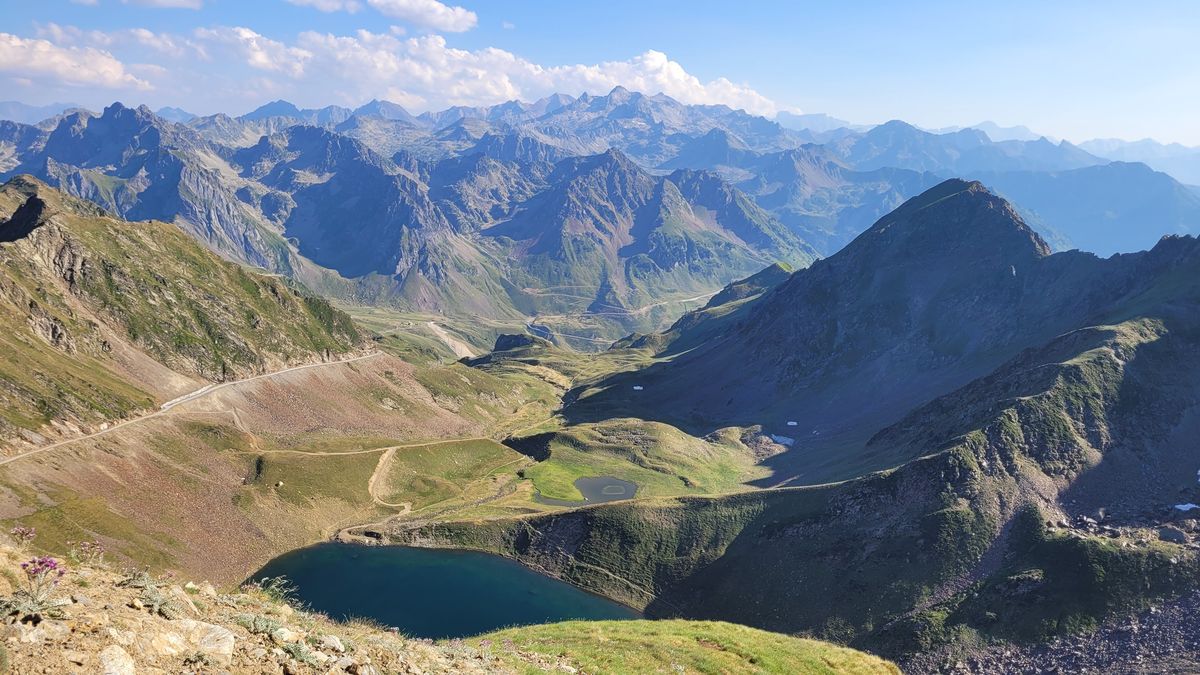 Vue plongeante sur le lac d'Oncet et la piste en lacets, crêtes du Néouvielle au fond, en juillet